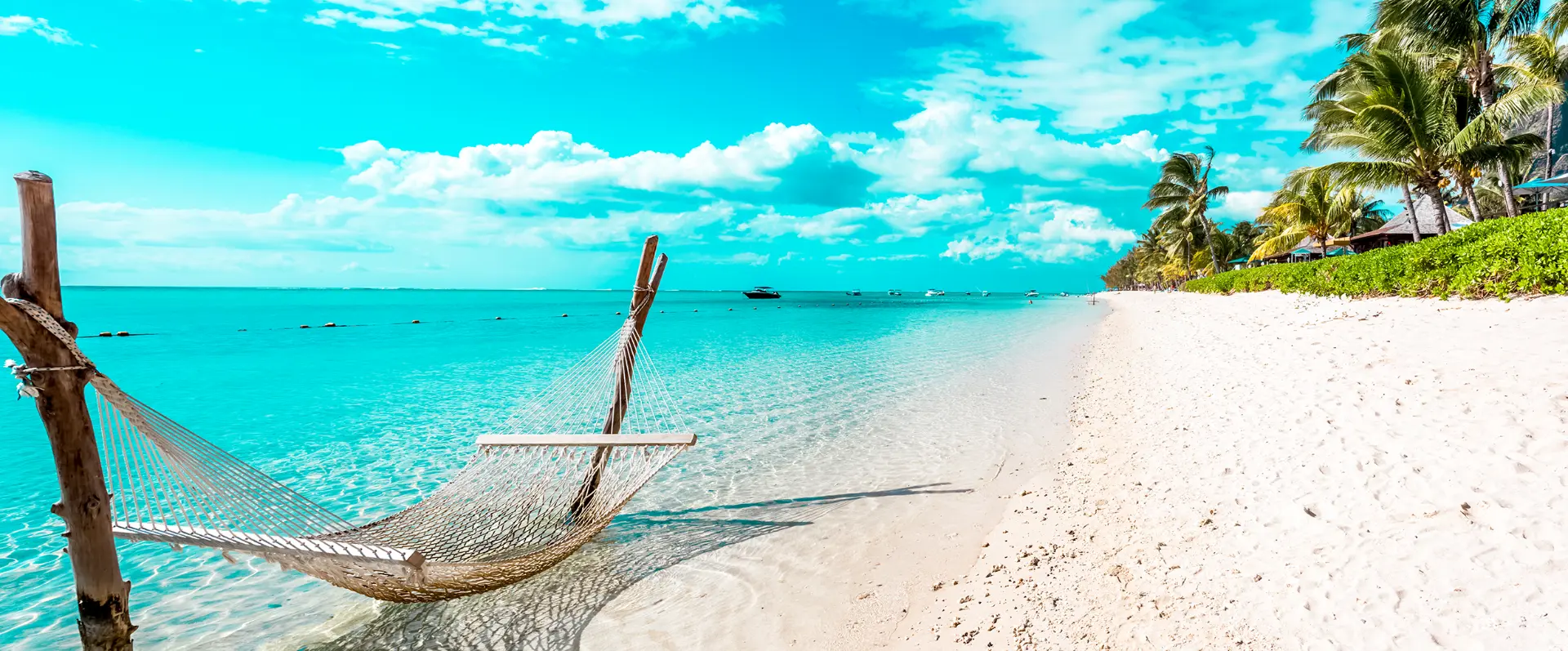 Hammock over clear turquoise Caribbean water on a white sand beach